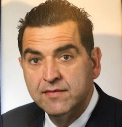 Head-and-shoulders portrait of George Petrovas in a suit and tie against a plain background.